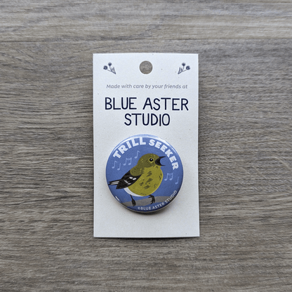 A 1.5 inch pinback button featuring an illustration of a pine warbler singing with the words "Trill Seeker" above it.