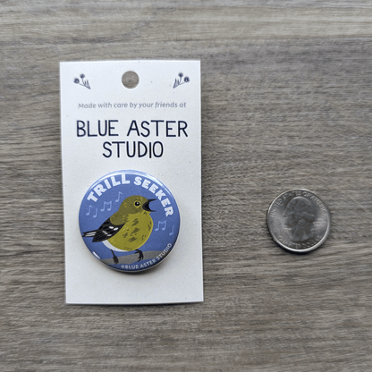 The warbler button sitting next to a USD quarter to show scale.