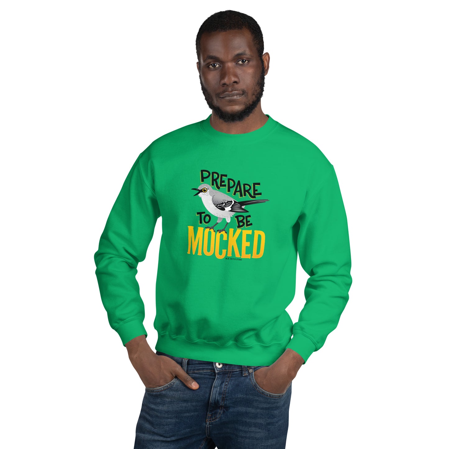 A green sweatshirt worn by a dark-skinned man with the text "prepare to be mocked" with an illustrated mockingbird perched within it