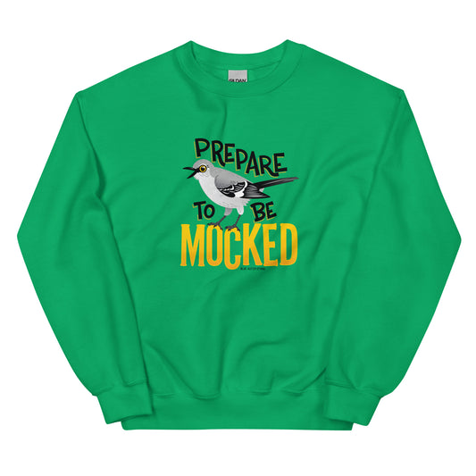 A green sweatshirt with the text "prepare to be mocked" with an illustrated mockingbird perched within it