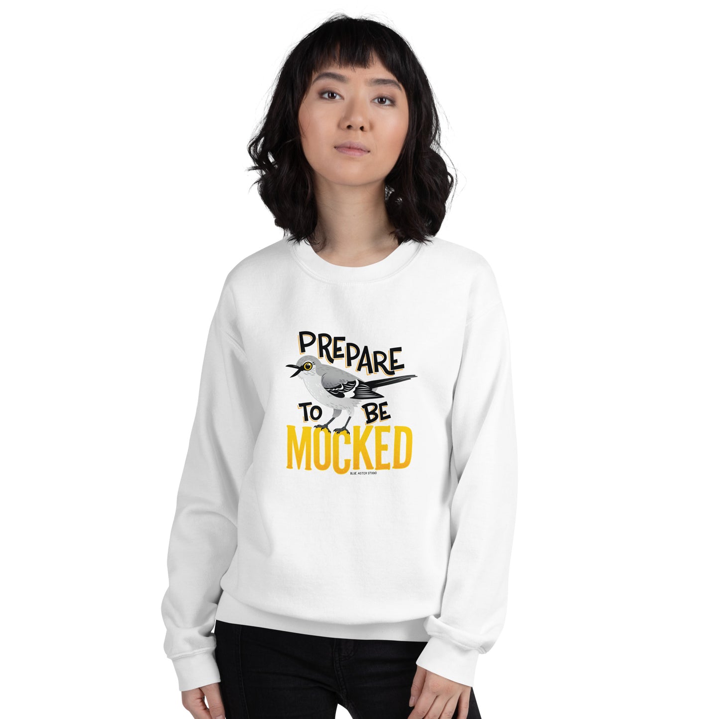 A white sweatshirt worn by a female model with the text "prepare to be mocked" with an illustrated mockingbird perched within it