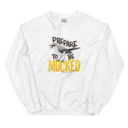 A white sweatshirt with the text "prepare to be mocked" with an illustrated mockingbird perched within it