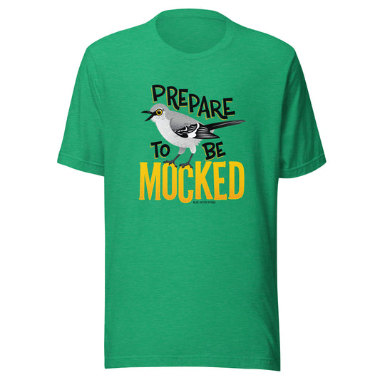 A green tee shirt with the text "prepare to be mocked" with an illustrated mockingbird perched within it