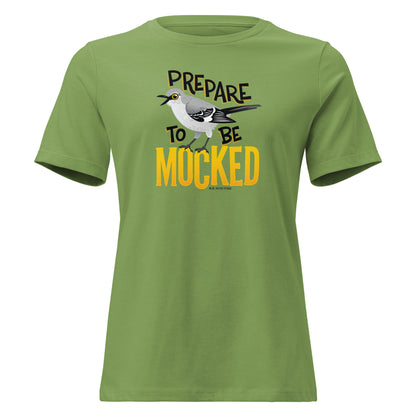 A green women's cut tee shirt with the text "prepare to be mocked" with an illustrated mockingbird perched within it