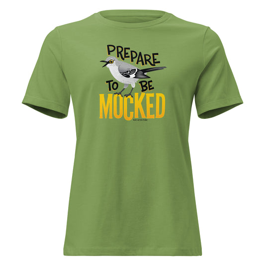 A green women's cut tee shirt with the text "prepare to be mocked" with an illustrated mockingbird perched within it