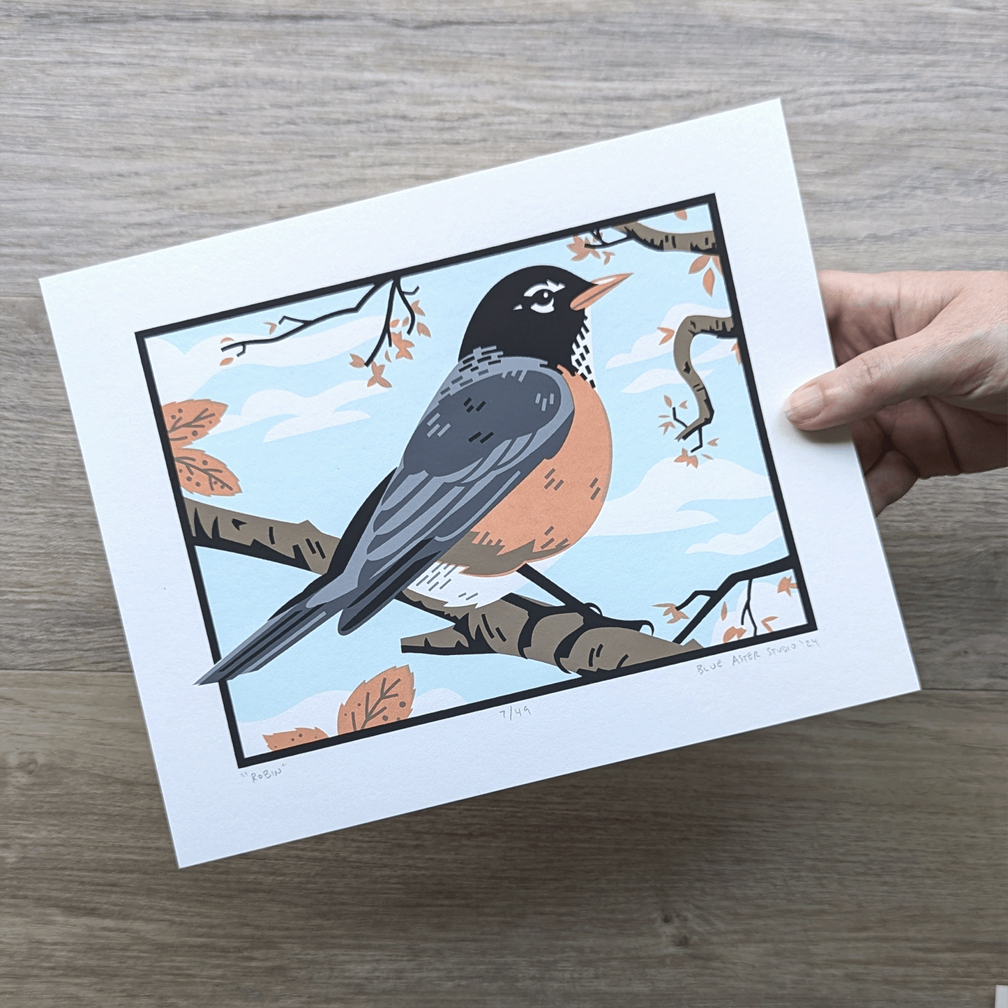 A hand holding the original 8x10 screen print of a robin to show scale.