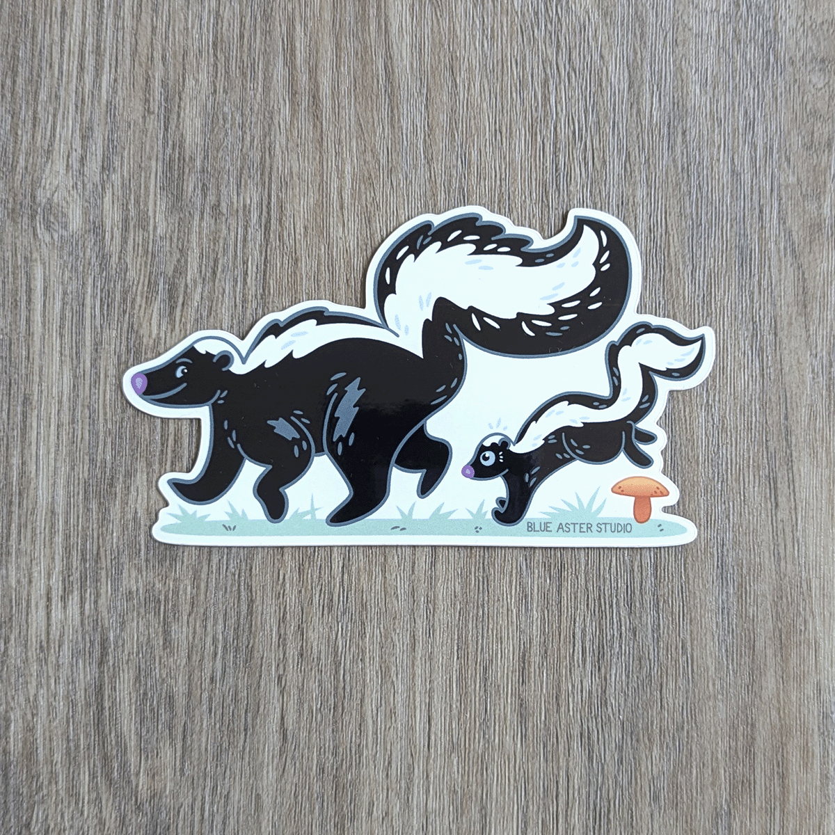 Sticker of an illustration of mama skunk with a baby skunk following behind.