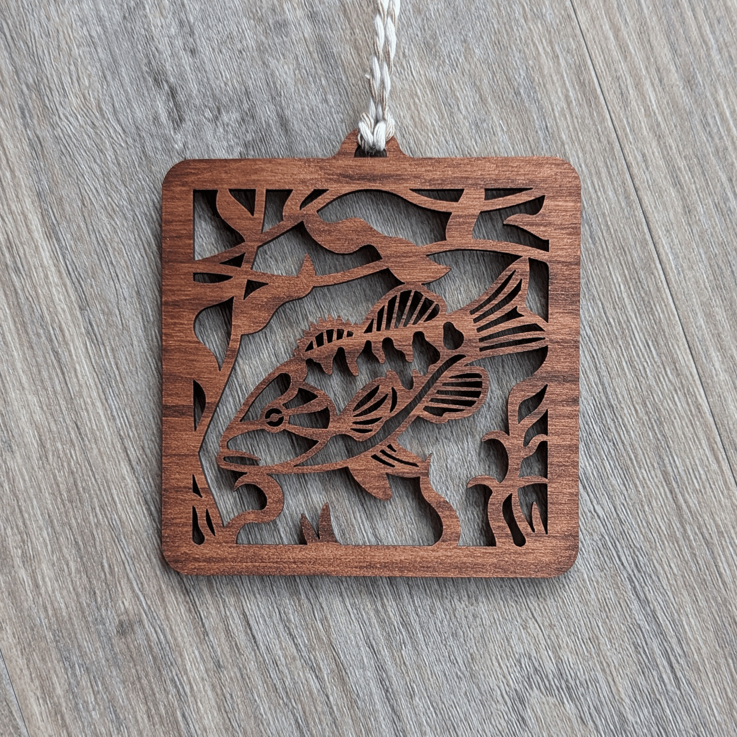 A square brown wooden ornament of a smallmouth bass.