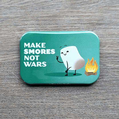 This refrigerator magnet features a cute illustration of a marshmallow toasting over an open fire with the words Make Smores Not Wars.