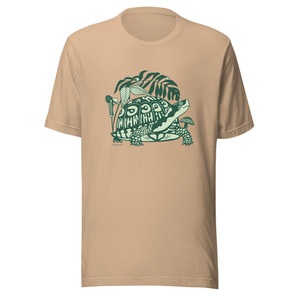 A tan t-shirt with a front design of a box turtle surrounded by North American native woodland plants.