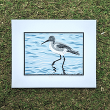 Load image into Gallery viewer, An original screen print of an illustration of a willet shorebird wading and foraging in shallow water. The print is sitting on a mossy background.