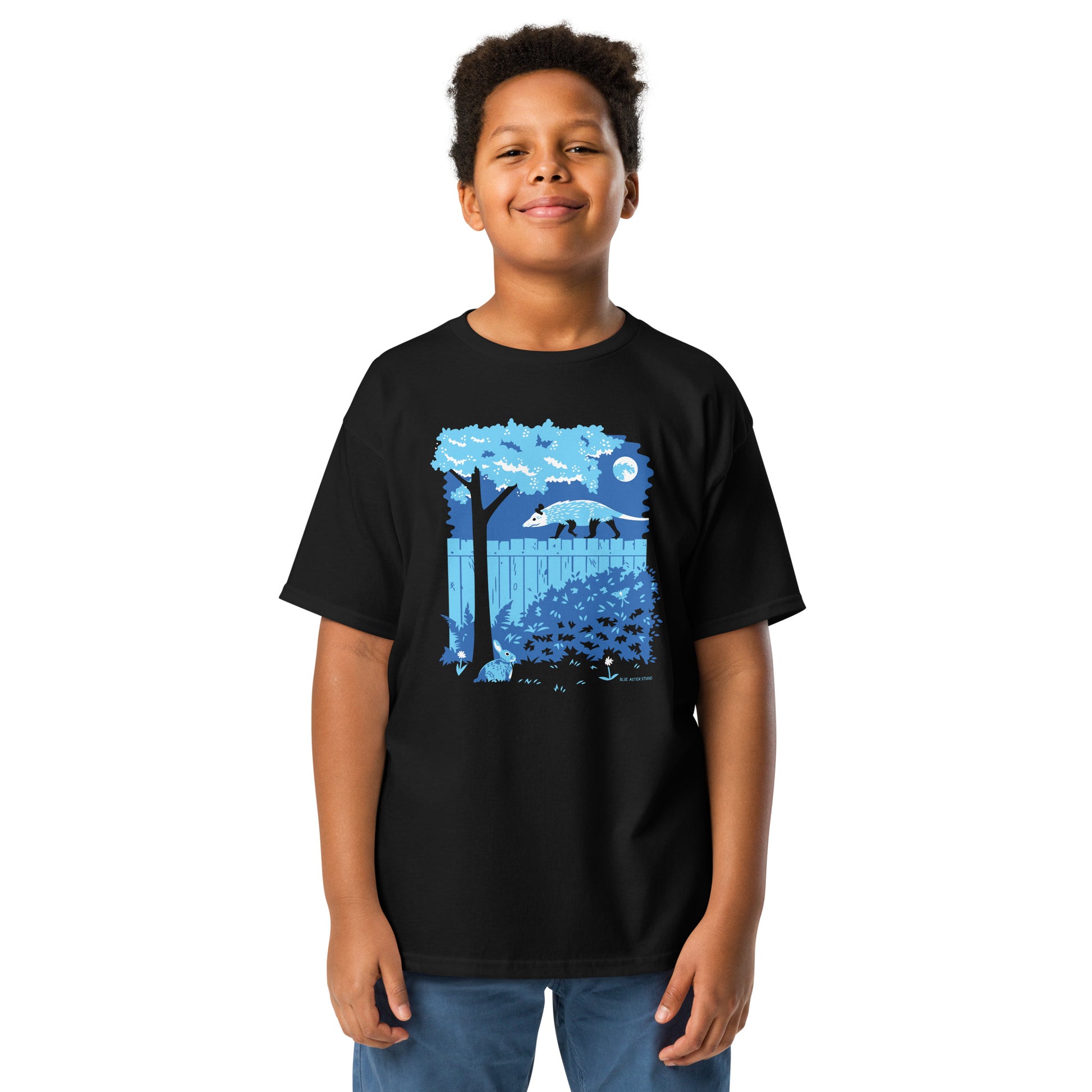 A young boy wearing the opossum and rabbit t-shirt in black.