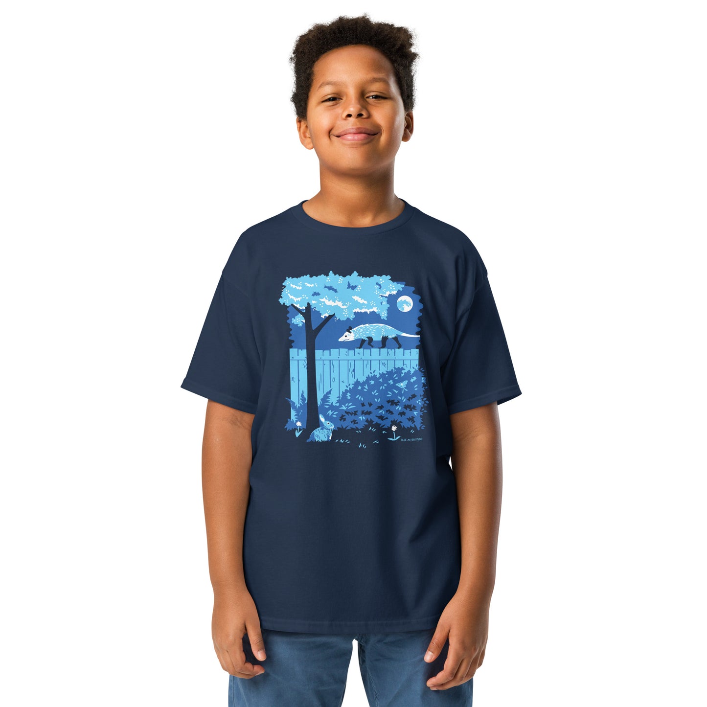 A young boy wears a navy colored t-shirt with an opossum and rabbit printed on the front.