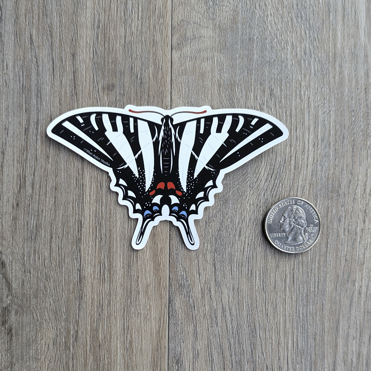 The zebra swallowtail sticker with a USD quarter coin for scale.