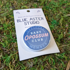 A close up shot of the Baby Opossum Club button.