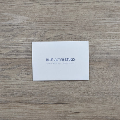 The back of the opossum card showing the Blue Aster Studio logo, website address, and that the cards are printed on recycled paper.