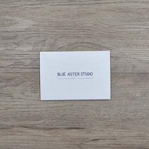 The back of the opossum card showing the Blue Aster Studio logo, website address, and that the cards are printed on recycled paper.