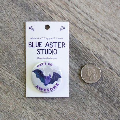 A 1.5" pinback button with an illustration of a bat flying in front of a full moon with the words "Bat's So Awesome" next to a USD quarter for scale.