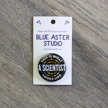 Load image into Gallery viewer, A 1.5 inch black pinback button with the words This Is What A Scientist Looks Like in white.
