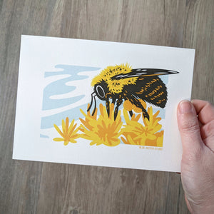 A bumblebee art print being held by a hand to show scale.
