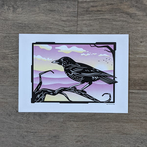 An art print of a crow perched on a dead tree branch silhouetted against a purple and yellow sunset sky.