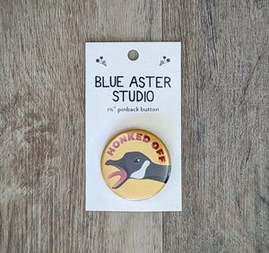 A 1.5 inch pinback button featuring an illustration of a goose with its beak open wide and the words "Honked Off" above it.