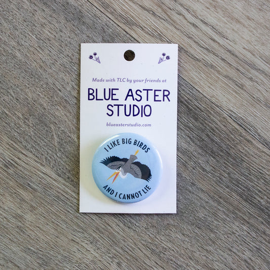 A 1.5" button with an illustration of a great blue heron on a light blue background and the words "I Like Big Birds And I Cannot Lie"