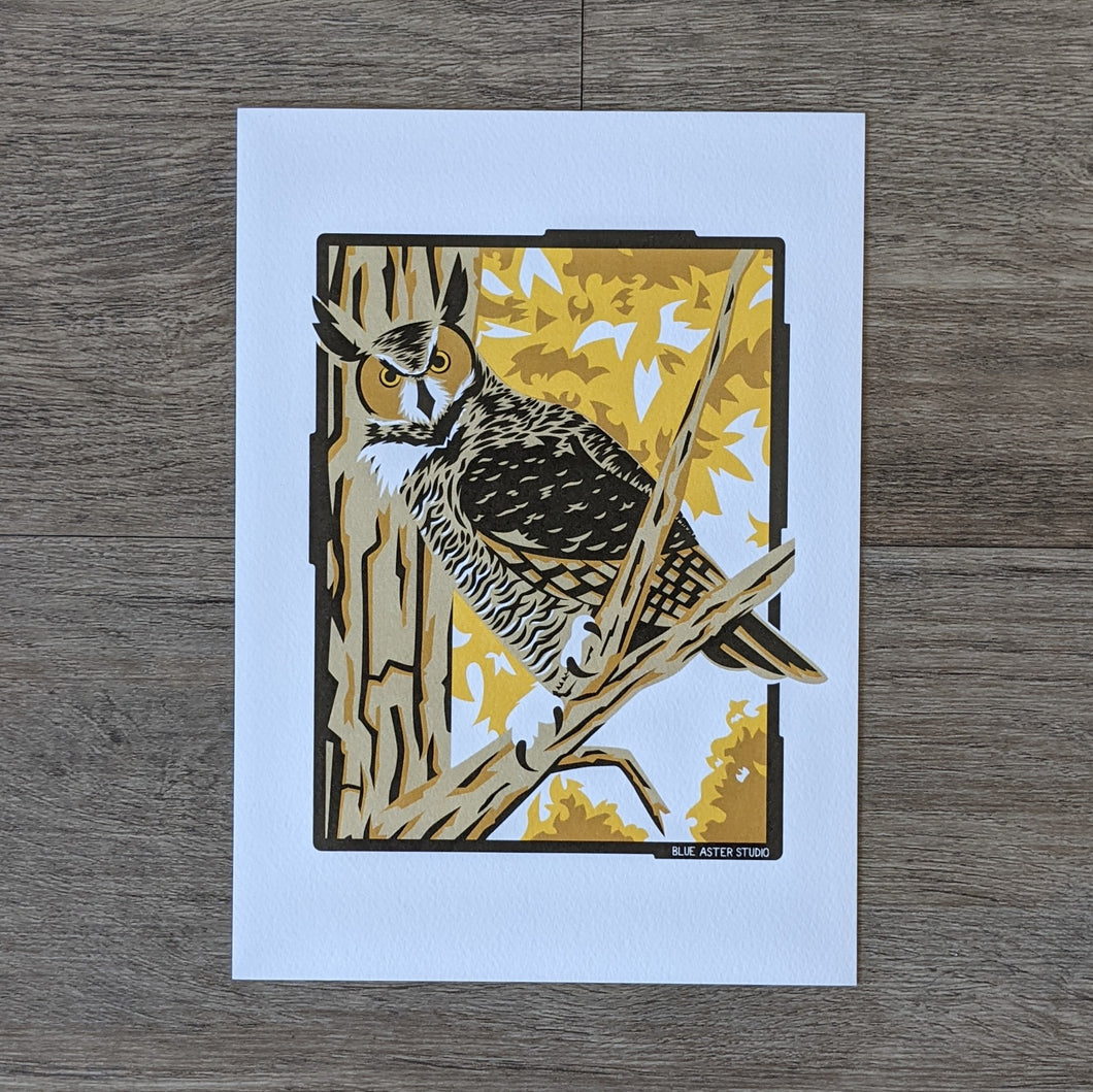 An art print of an illustration of a great horned owl perched in a tree surrounded by fall folliage.
