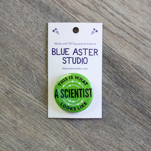 A 1.5 inch green pinback button with the words This Is What A Scientist Looks Like in black.