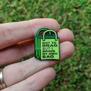 The reusable bag enamel pin being held in a hand to show detail.