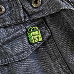 The Not To Brag But I Bring My Own Bag enamel pin shown pinned to a gray canvas jacket.