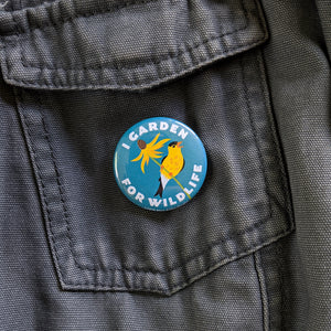 A 1.5 inch "I Garden For Wildlife" button pinned to a gray canvas jacket.