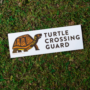 A 2.5 by 7.5 inch vinyl bumper sticker with an illustration of a box turtle and the words "Turtle Crossing Guard" next to the illustration.