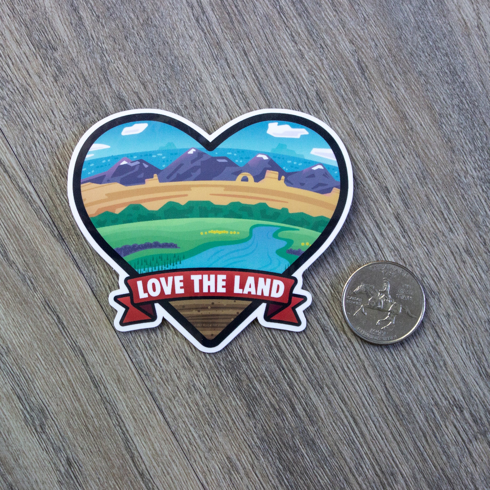 The Love The Land vinyl sticker sitting next to a USD quarter for scale.