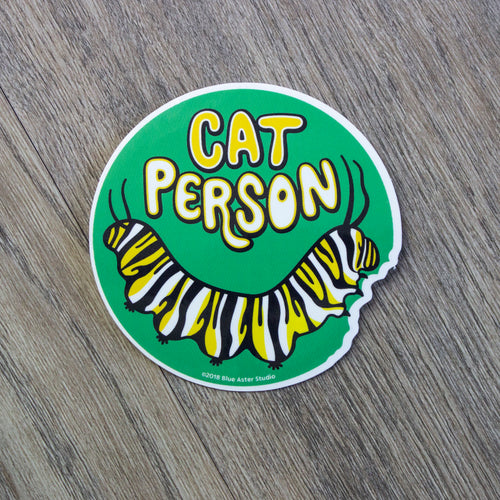 A round vinyl sticker with an illustration of a monarch caterpillar and the words Cat Person above it.
