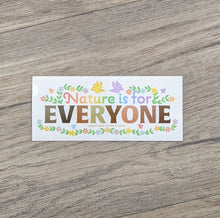 Load image into Gallery viewer, A rectangular vinyl sticker with the words &quot;Nature Is For&quot; in rainbow colors and &quot;Everyone&quot; with each leter in shades of skin tones surrounded by flowers and birds