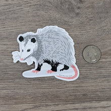 Load image into Gallery viewer, A vinyl sticker of an illustrated opossum next to a USD quarter for scale.