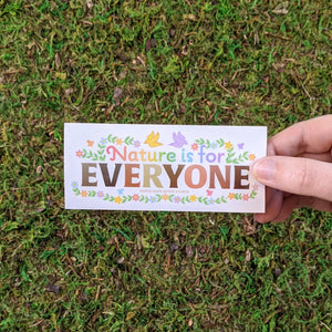 Hand holding a rectangular vinyl sticker with the message "Nature Is For Everyone"