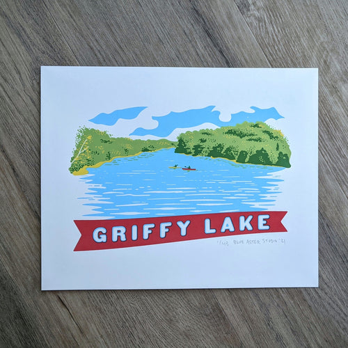 A scene of Griffy Lake in Southern Indiana screen printed in the style of vintage postcard art. The scene shows two kayakers on the water surrounded by the green tree line and a banner at the bottom that reads 