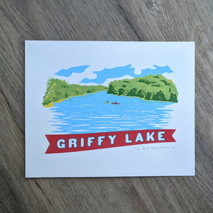 A scene of Griffy Lake in Southern Indiana screen printed in the style of vintage postcard art. The scene shows two kayakers on the water surrounded by the green tree line and a banner at the bottom that reads "Griffy Lake"