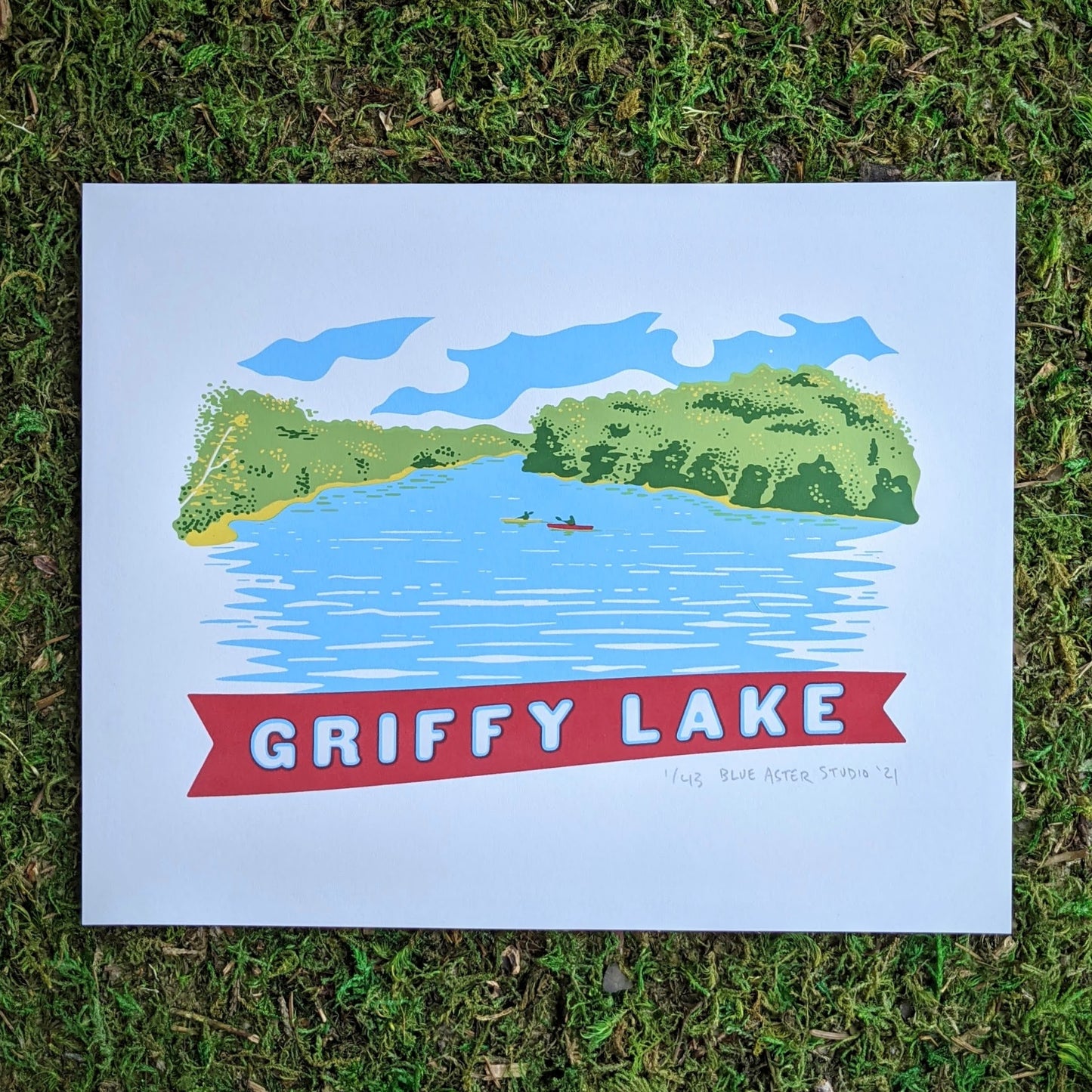 A scene of Griffy Lake in Southern Indiana screen printed in the style of vintage postcard art. The scene shows two kayakers on the water surrounded by the green tree line and a banner at the bottom that reads "Griffy Lake"