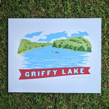 Load image into Gallery viewer, A scene of Griffy Lake in Southern Indiana screen printed in the style of vintage postcard art. The scene shows two kayakers on the water surrounded by the green tree line and a banner at the bottom that reads &quot;Griffy Lake&quot;