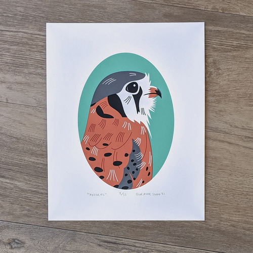 A handmade screen print of an American kestrel framed by a teal oval. The print is numbered 2 of 35.