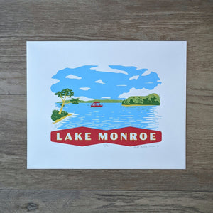 A scene on Lake Monroe that shows a pontoon boat and some swimmers surrouned by the treen lined shore of the Southern Indiana lake. At the bottom is a banner that reads "Lake Monroe." The screen print is inspired by vintage postcard art.