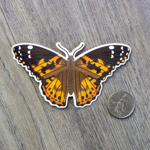 A vinyl sticker of a painted lady butterfly sitting next to a USD quarter for scale.