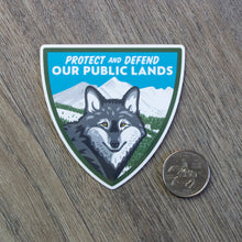 Load image into Gallery viewer, The Protect And Defend Our Public Lands wolf sticker sitting next to a USD quarter to show scale.