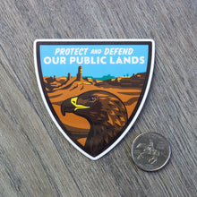 Load image into Gallery viewer, The Protect And Defend Our Public Lands Golden Eagle sticker sitting next to a USD quarter for scale.
