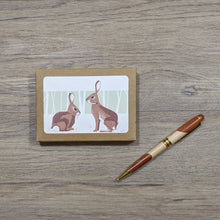 Load image into Gallery viewer, An 8 pack of rabbit cards with envelopes. The package is a kraft paper box with a window opening which reveals the design of the rabbit cards.