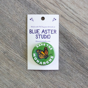 A 1.5 inch green pinback button with an illustration of a monarch butterfly in flight and the words Save The Monarchs.