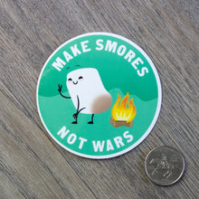 Load image into Gallery viewer, The Make Smores Not Wars vinyl sticker sitting next to a USD quarter for scale.